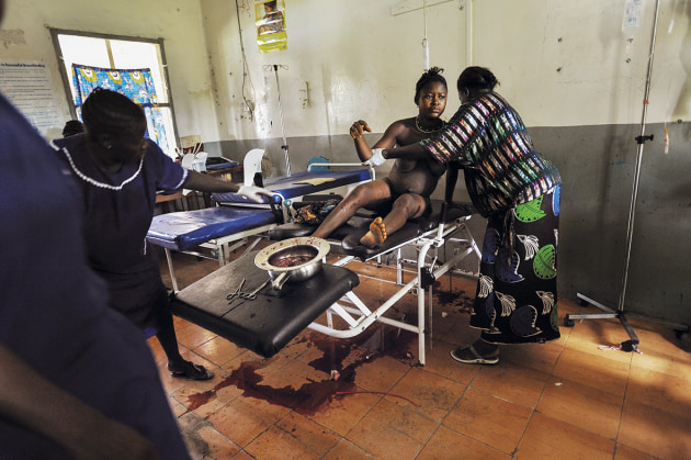 © Lynsey Addario. Blood continues to leak from Mamma Sesay (18) shortly after she delivered the second of twins, as her sister, Amenata, helps clean her body at the Magburaka Government Hospital, in Sierra Leone, 2010. At 14, she was forced to marry a man of about 50, and delivered her first child at 15.
Mamma said repeatedly 'I am going to die' as she lay on the delivery table.