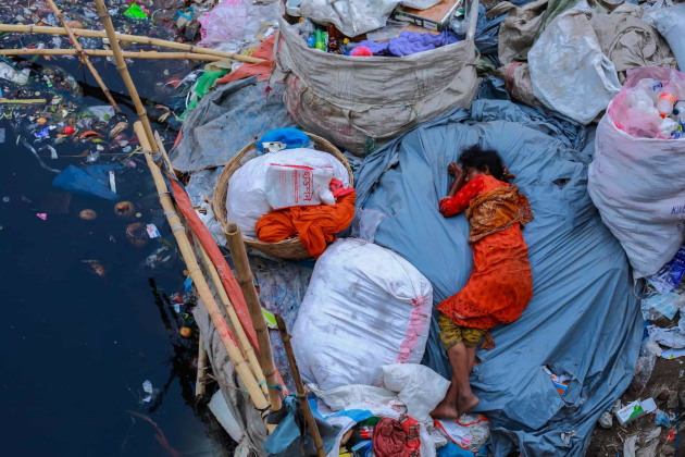 Photograph: Amdad Hossain/2019 CIWEM Environmental Photographer of the Year. Sleep Fatigue. A woman sleeps on a dirty riverbank, Dhaka, Bangladesh.