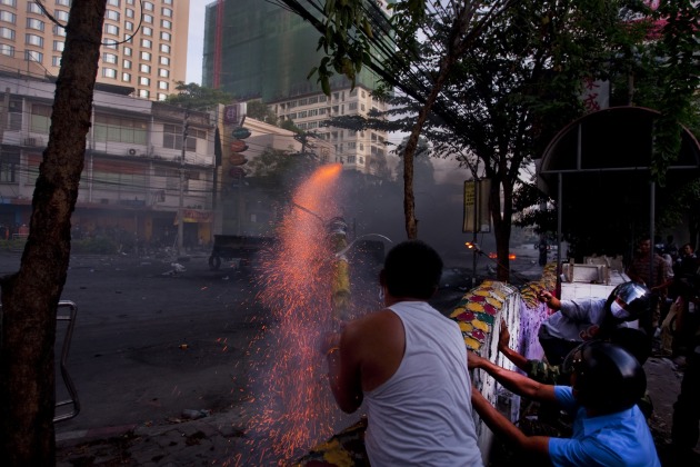 Street fighting near a major intersection in the heart of Bangkok during the 2010 so-called ‘Redshirts’ uprising. ‘Redshirts’ fighters launch a homemade rocket-propelled grenade at government soldiers. © Jack Picone.