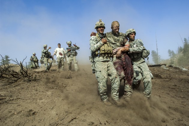 Specialist Carl Vandeberge, centre, and Sargeant Kevin Rice, behind, are assisted as they walk to a medevac helicopter minutes after they were both shot in the stomach during a Taliban ambush, which also killed one soldier. Korengal Valley, Afghanistan, 23 October, 2007. © Lynsey Addario.