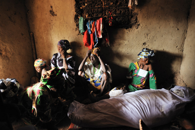 In a ritual performed in villages throughout Sierra Leone, villagers cover the face of the deceased with powder to ward off evil, and prepare her for the afterlife. Maria Komeh, the stepmother of Mamma Sessay, weeps over her body as female relatives bid goodbye to Mamma Sessay before her burial in the village of Mayogbah the day after her death from postpartum haemorrhaging, in Sierra Leone, 20 May, 2010. © Lynsey Addario.