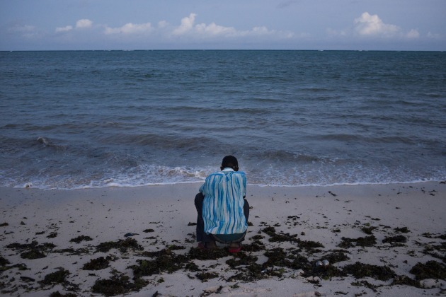 © Alex Potter. M looks out to sea on the south coast of Mombasa, Kenya on April 11, 2016. M returned to Mombasa after defecting from Al Shebaab. He spent over five years in Somalia, and fears every day the police will take him from his family in Mombasa.