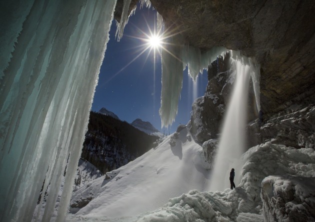 © Paul Zizka. The full moon bursts through the hanging icicles of the partially frozen Panther Falls, Banff National Park, Canada.