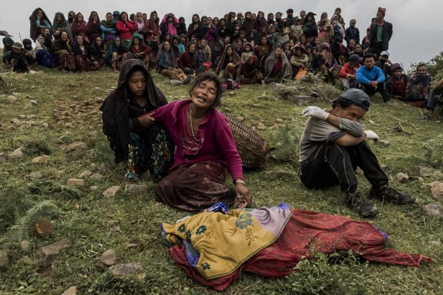 © Daniel Berehulak. Bishnu Gurung (centre) weeps as the body of her daughter, Rejina Gurung, 3, recovered from the rubble of her earthquake-destroyed home, lays covered by cloth during her funeral on 8 May, 2015 in the village of Gumda, Nepal. Neighbours discovered the body of the small girl in the rubble of the entrance of the family home, ending a 13 day search for Rejina in the remote mountainside village.