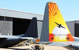 The scheme depicts a bright yellow and orange sunset motif, with the silhouette of a C-130H Hercules.