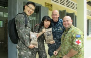 Flight Lieutenant Ben James of the Royal Australian Air Force (right) treats himself to a US Military Meal Ready to Eat with nurses from the US Navy and the Republic of Korea (ROK) during a MEDCAP at Takeo Teacher Training Centre