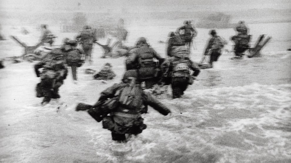 Robert Capa
International Center of Photography/Magnum Photos

American soldiers landing on Omaha Beach, D-Day, Normandy, France. June 6, 1944.

“The water was cold, and the beach still more than a hundred yards away. The bullets tore holes in the water around me,
and I made for the nearest steel obstacle… It was still very early and very gray for good pictures, but the gray water and the gray sky made the little men, dodging under the surrealistic designs  of Hitler’s anti-invasion brain trust, very effective.”

–Robert Capa, Slightly Out of Focus (1947)