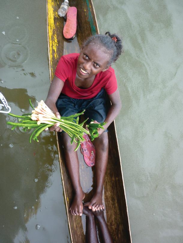 Kids in canoes trying to sell vegetables.