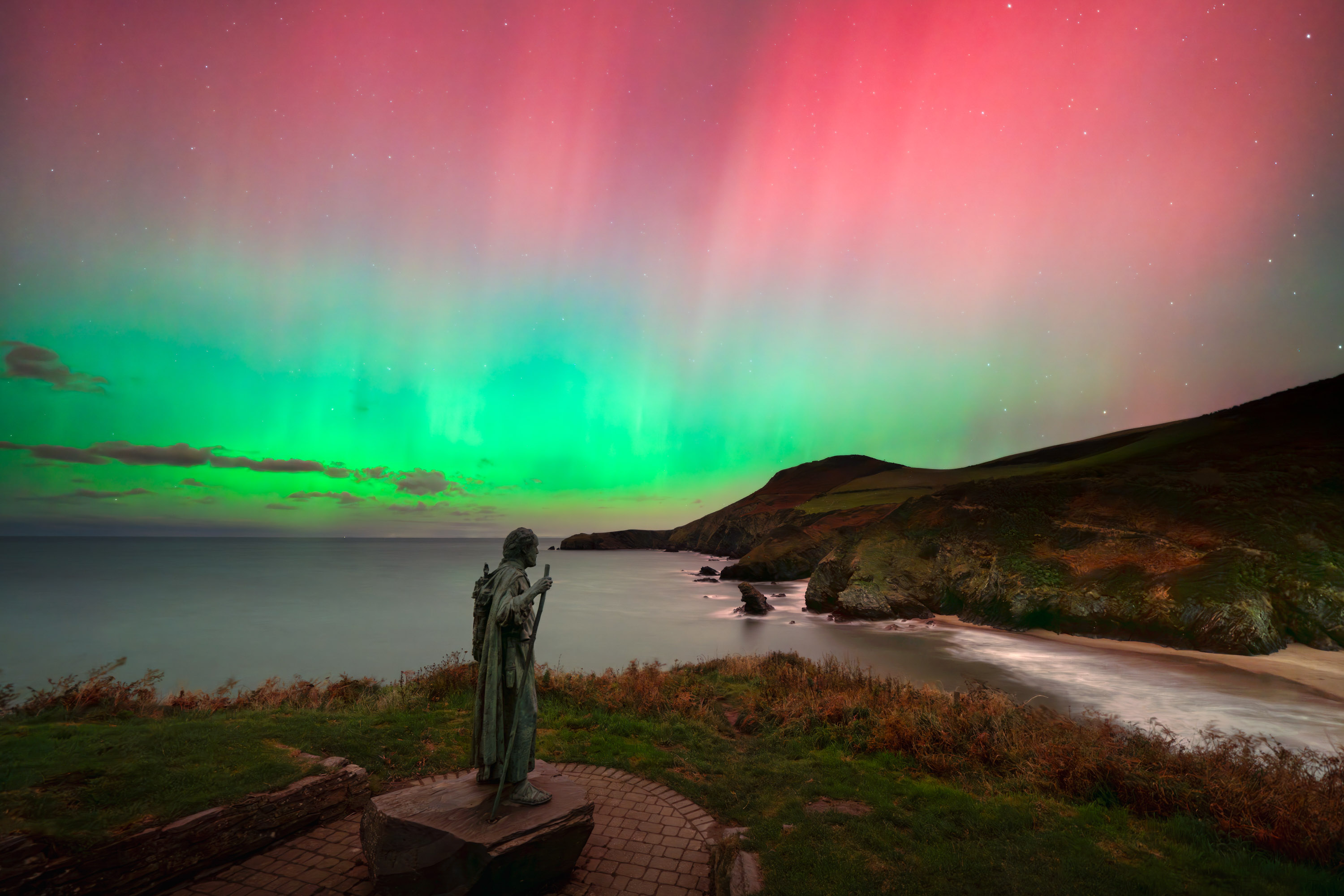 “Llangrannog Aurora” – Mathew BrowneLlangrannog, Ceredigion coast, WalesI was overjoyed to capture this otherworldly Northern Lights display on the rugged Ceredigion coast of West Wales. The village of Llangrannog is not known for its celestial displays; it is better known for its beach, dramatic cliffs, and the statue of St. Crannog, who stands watch over the shoreline.Because sightings of the aurora in this part of Wales are so uncommon (this location lies 52 degrees north), each image I’ve captured is an intersection of preparation, great timing, clear skies, and, of course, a bit of luck.