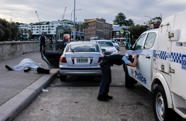 Title: Bondi Beach Terror Attack. © Edwina Pickles, The Sydney Morning Herald.
An overwhelmed police officer leans over near the bodies of Boris (69) and Sofia (61) Gurman. During the Bondi Beach Terror Attack, the couple were killed while attempting to disarm one of the shooters. Sydney, Australia, 14 December 2025.
