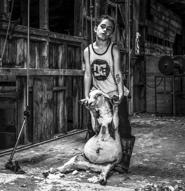 People Category Winner, Amy Hughes, In the shearing sheds. Amy Hughes’ People category winning image In the shearing sheds depicts her eight-year old son Kahu. For Hughes, the image tells a layered, authentic story. “The image speaks to rural life, generational roles, and the connection between humans and animals,” she says.