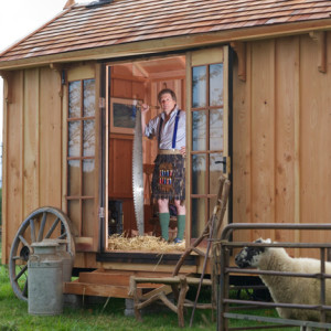 Chippendale School principal Anselm Fraser (in wooden kilt) before one of the school's recent shepherd's hut projects.