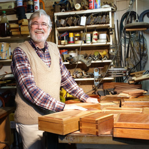 Morris Lake in his workshop with a selection of boxes that he has made from a variety of native species.