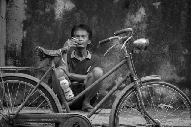 Ubud, Bali. I came across this man sat behind his bike in a backstreet. The antiquity of the bike and the intensity of his stare make for a different take on the polished perfection of Ubud. Fujifilm X-T1, 18-55mm f/2.8-4 lens @ 55mm. 1/220s @ f4, ISO 400.
